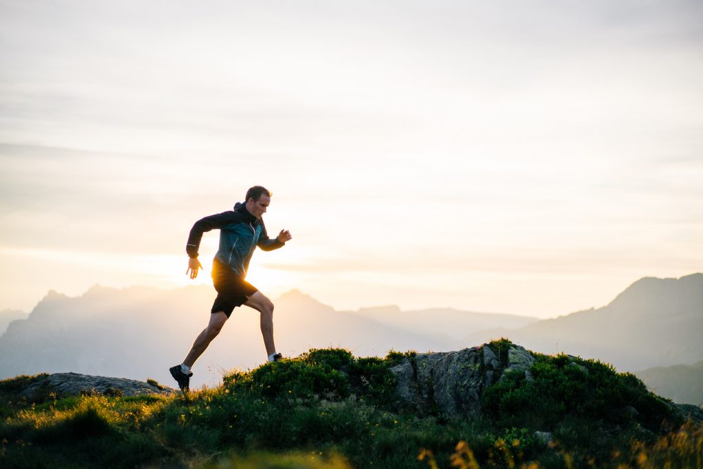 Young man fulfills his new years resolution, runs on mountain ridge at sunrise