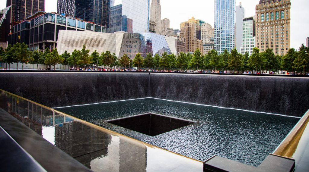 National September 9/11 memorial waterfalls with surrounding buildings in Lower Manhattan.