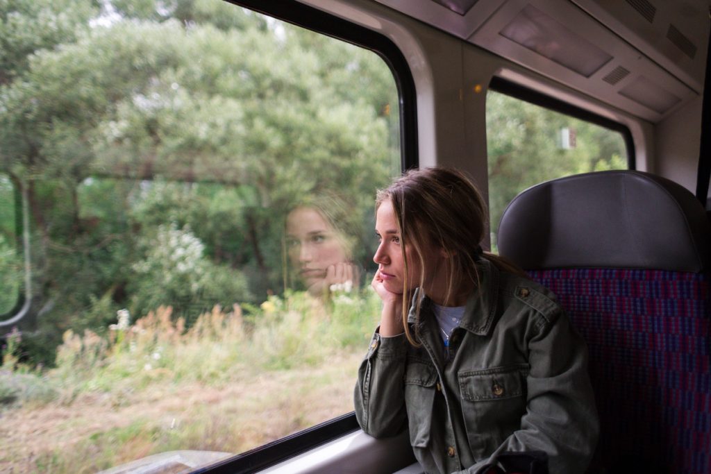 Young adult woman sitting inside a train while looking outside the window