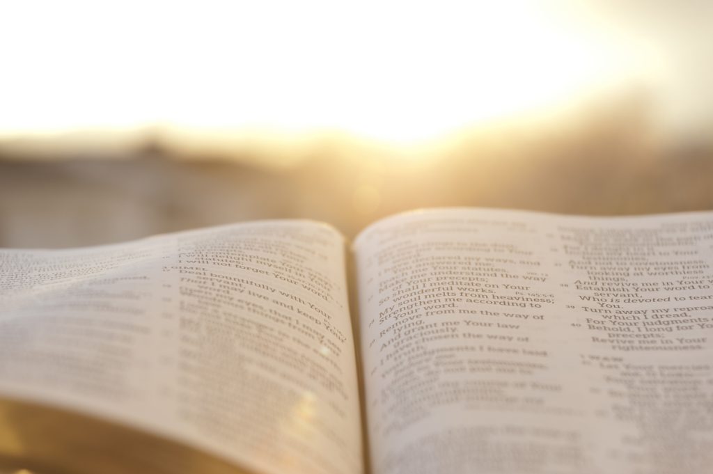 OpenBible with bright sunset in the background. Close-up. Horizontal shot.
