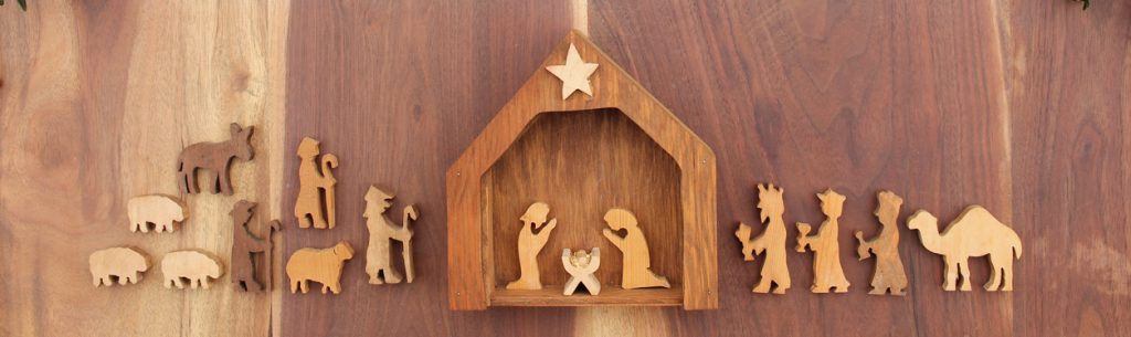 christmas nativity on a wood background with red berries and greenery
