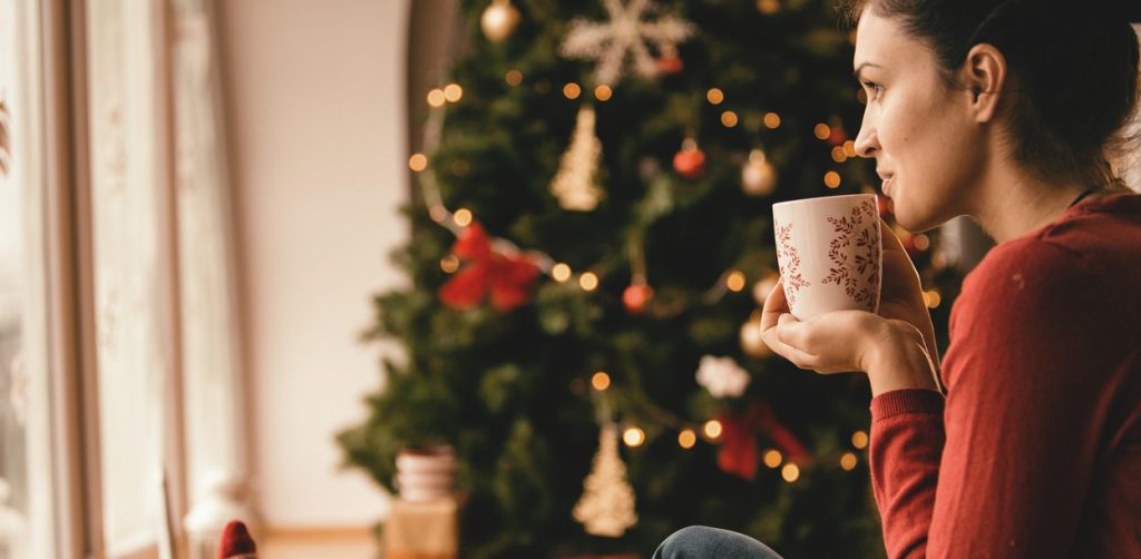oung woman drinking tea by the Christmas tree