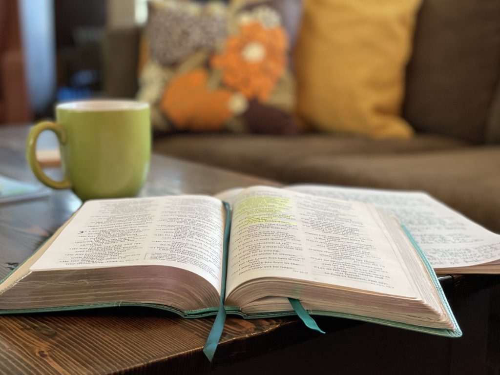 Renewal of mind with Bible Study time with bible open on table, lime-green coffee cup and pillows on the couch in the soft focus background