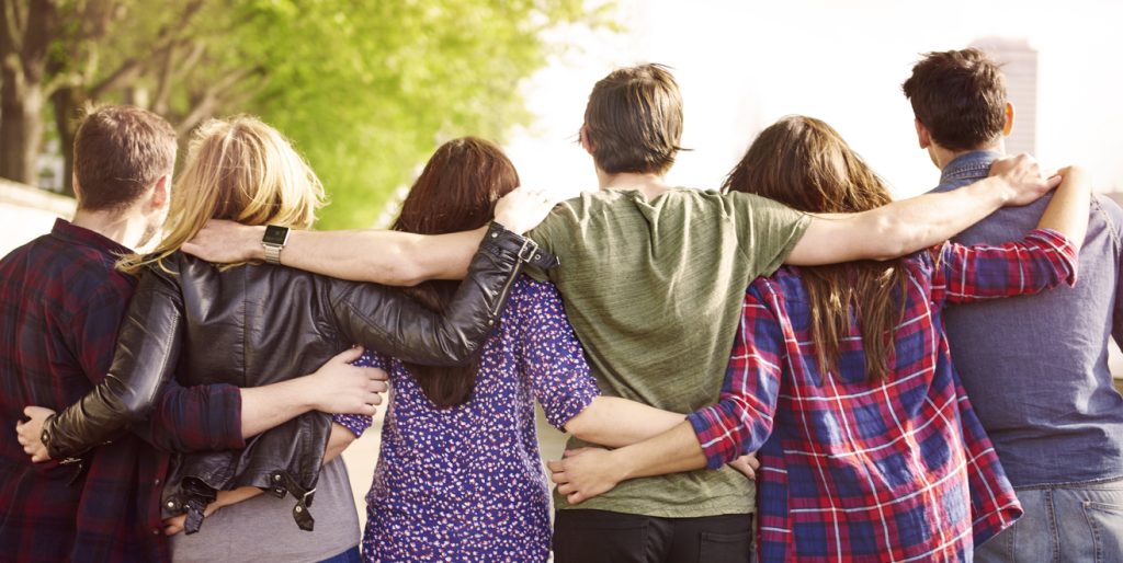 A crowd of friends with arm around each other, giving positive touch