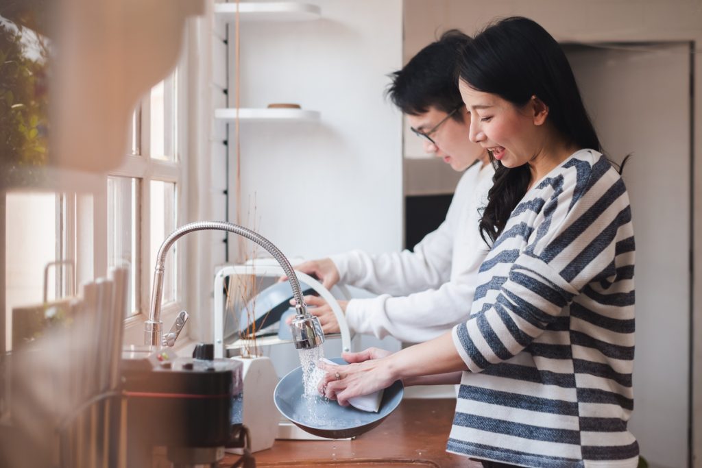 Asian couple family doing chores washing dishes together at kitchen