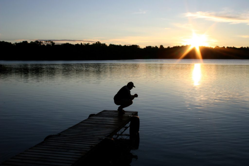 The silhouette of a man on a dock during sunset