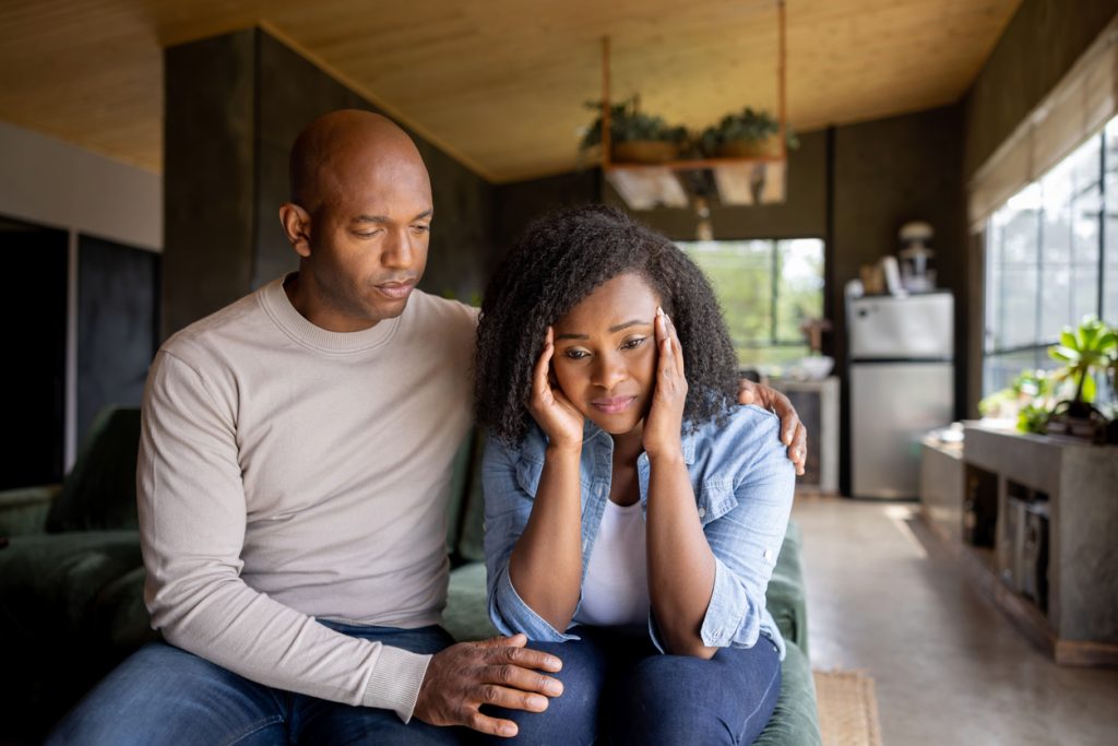 Loving African American husband consoling his sad wife at home - relationship concepts/secrets