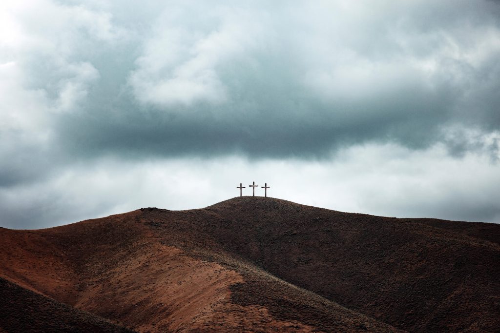 Three crosses on a desert hill. Dark clouds are looming overhead