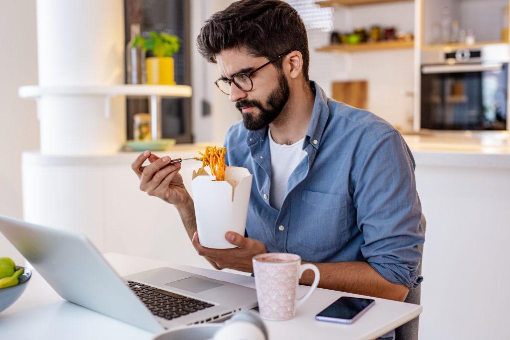 A young man is worried, he is using a laptop and working from home, stress eating